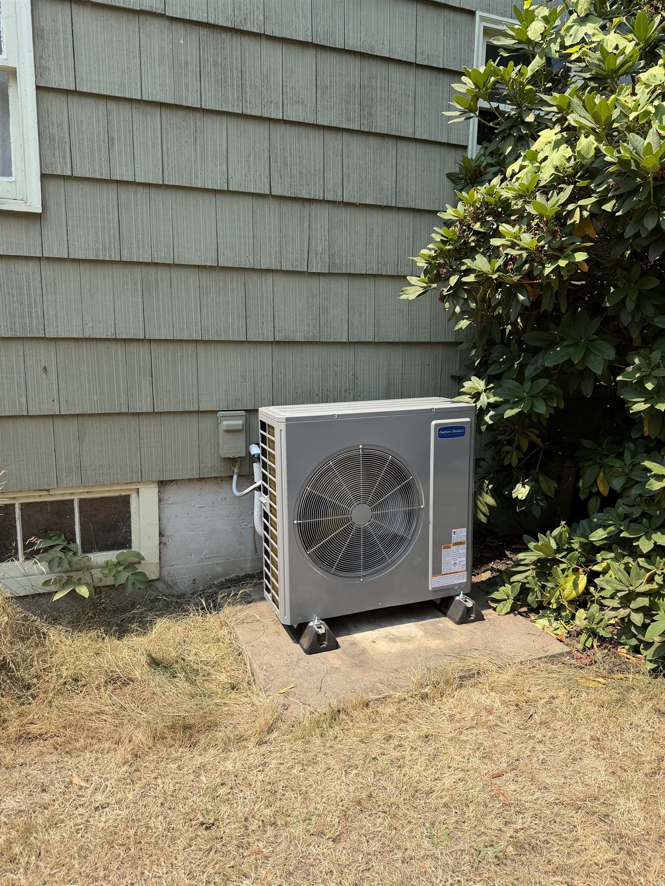 An outdoor heat pump on a pad beside a house