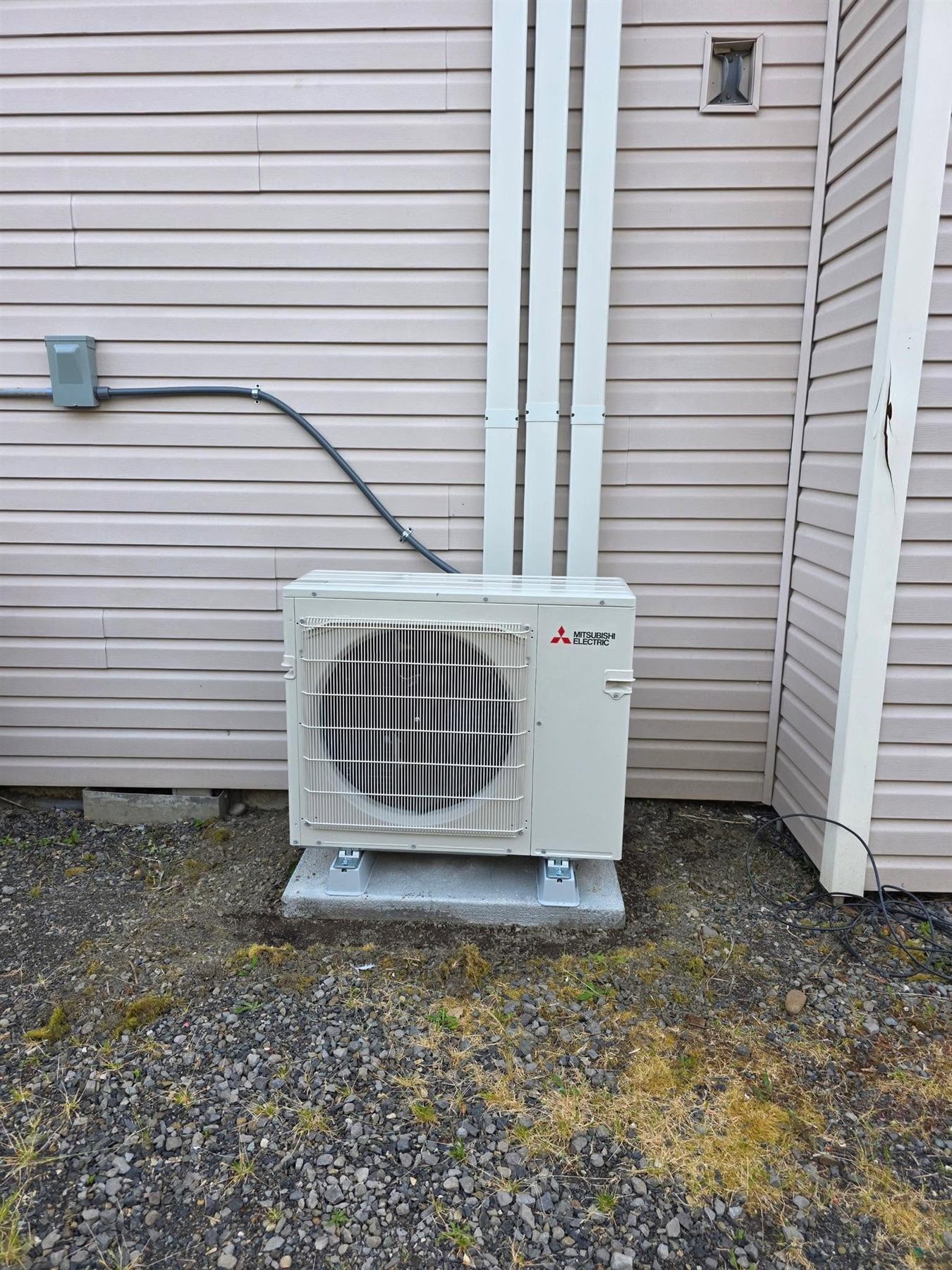 Mitsubishi outdoor heat pump installed beside a house